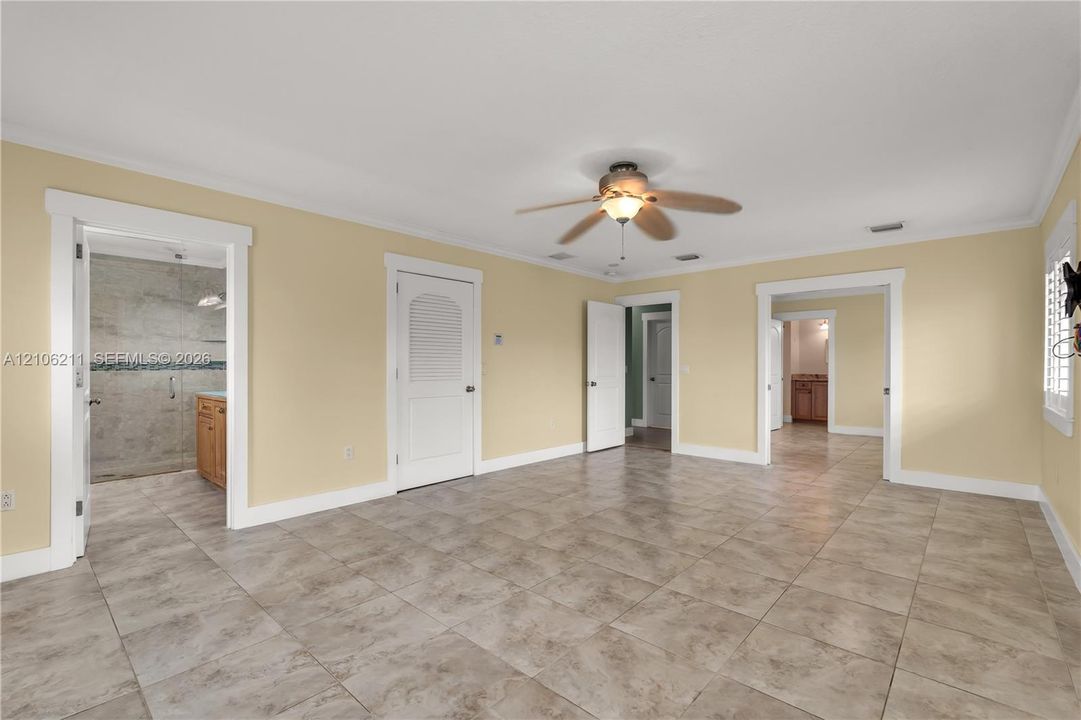 Spacious room featuring tile flooring, a central ceiling fan with integrated lighting, recessed lighting, and multiple arched door frames