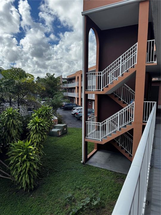 Multi-level exterior structure featuring arched architectural detailing, white metal railings, and painted stucco finishes