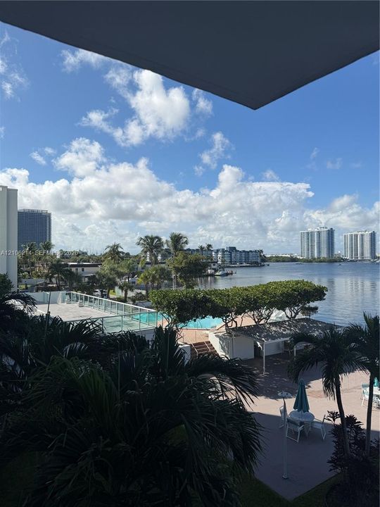 Elevated exterior perspective featuring a swimming pool, paved sundeck, pergola-covered seating area, and waterfront access