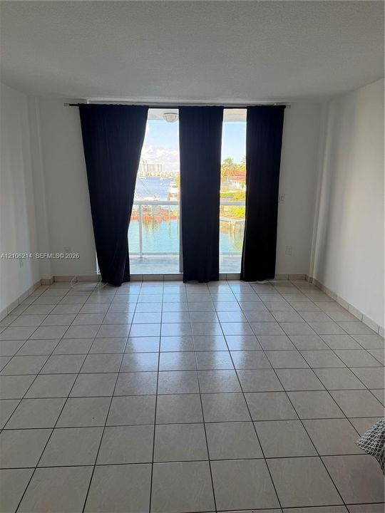 Interior space featuring ceramic tile flooring, floor-to-ceiling glass sliding doors, and a private balcony overlooking the water