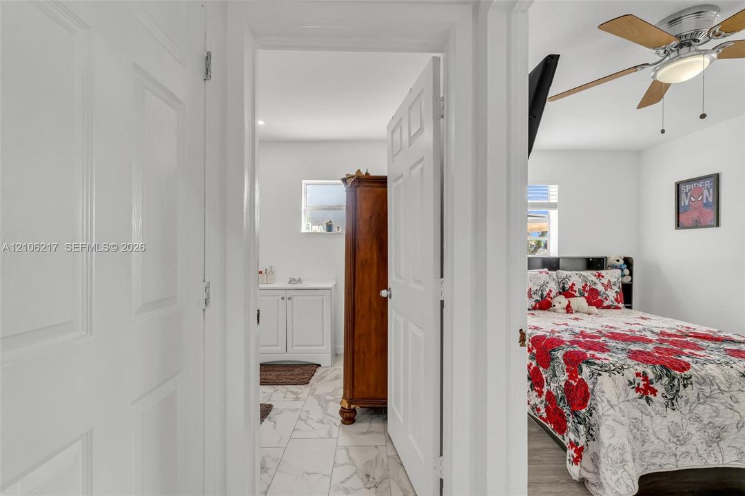 Interior doorway featuring a white six-panel door, ceiling-mounted light fixture with fan blades, and tile flooring