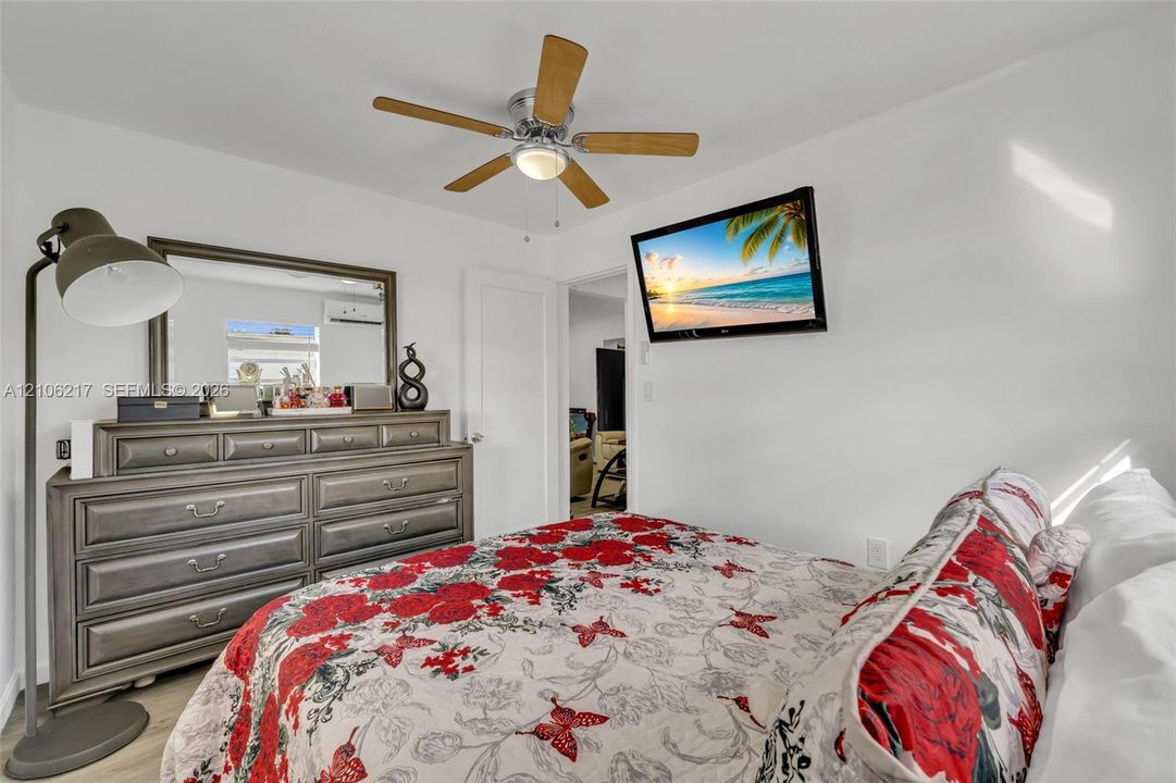 Room featuring a multi-blade ceiling fan with integrated lighting and a wall-mounted ductless mini-split unit