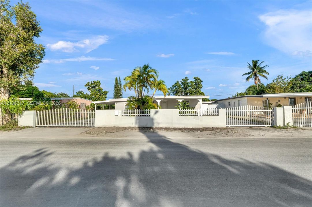 Exterior facade featuring a covered entryway, concrete perimeter wall, and gated entry