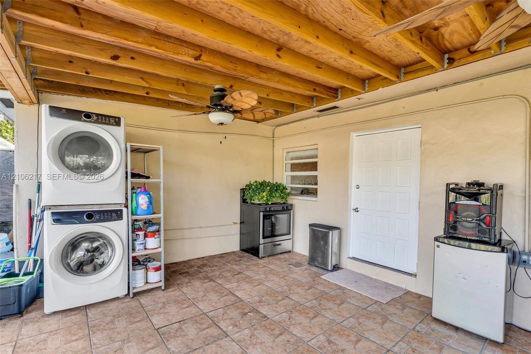 Covered outdoor space featuring exposed wood-beam ceiling, tile flooring, and a ceiling-mounted fan