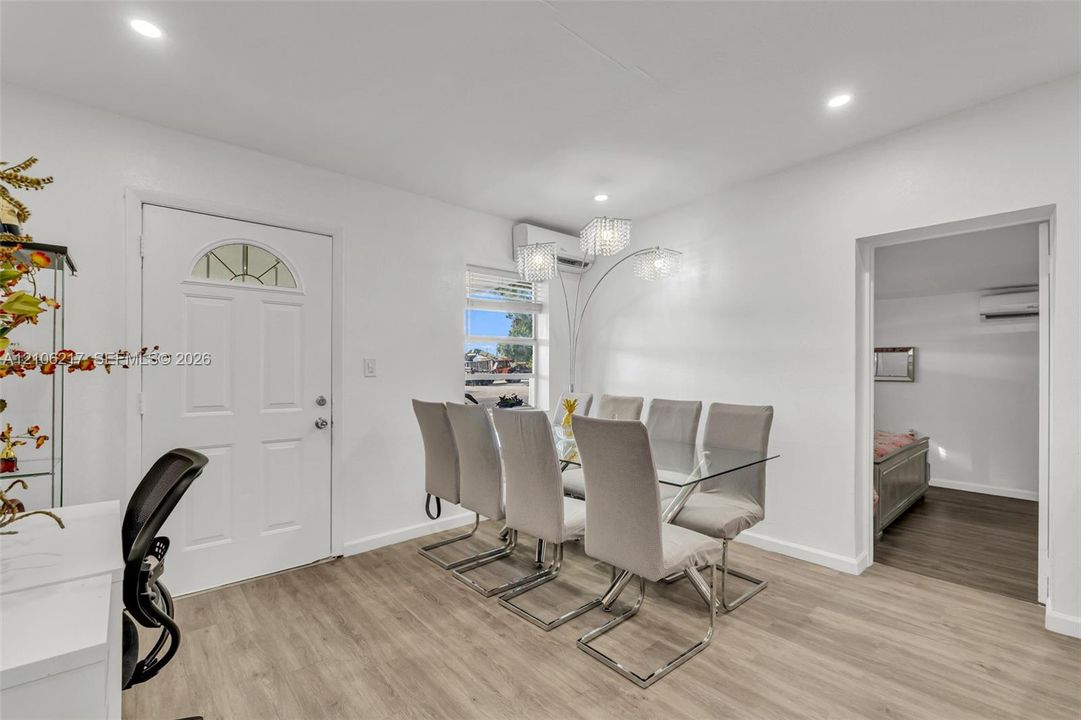 Interior space featuring light-toned wood-finish flooring, recessed lighting, multi-light chandeliers, and a wall-mounted ductless heating and cooling unit