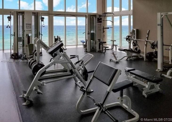 Fitness center featuring floor-to-ceiling windows, ocean horizon exposure, and resilient rubberized flooring