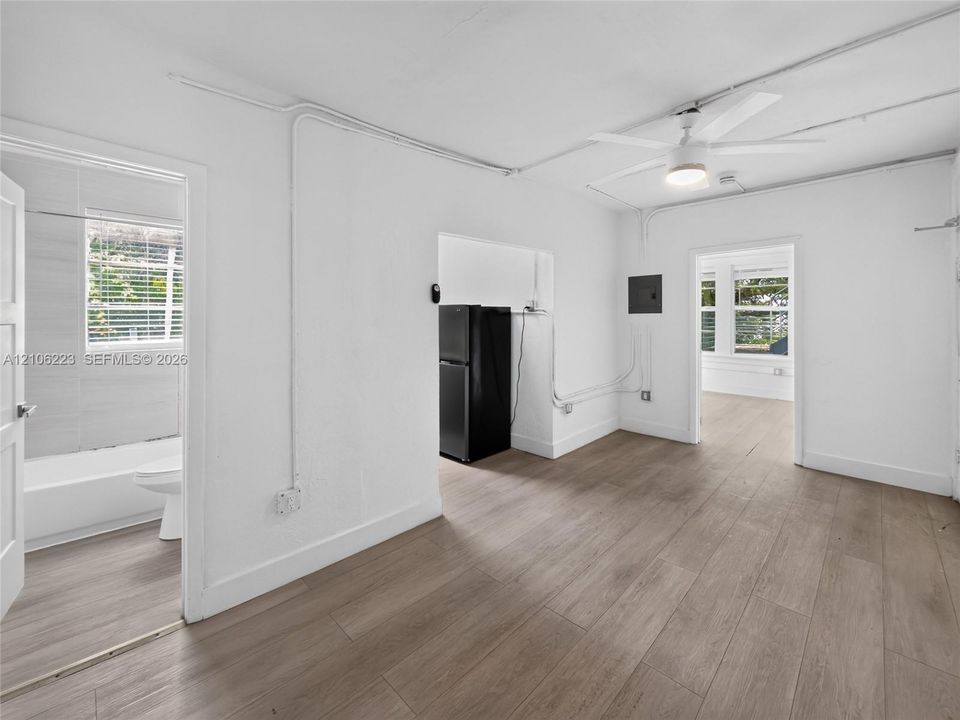 Interior space featuring wood-finish flooring, white walls, a ceiling fan with integrated lighting, and multiple entryways