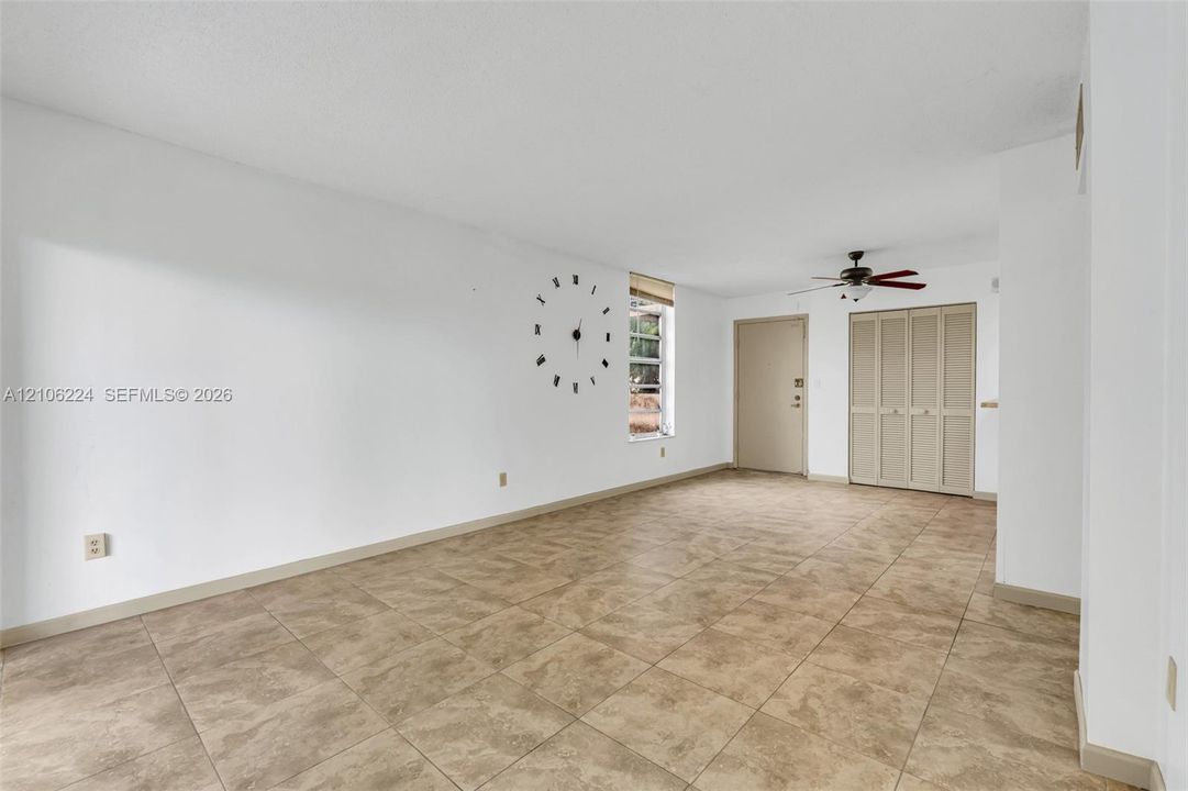 Neutral-toned tile flooring, ceiling fan with light fixture, and bi-fold closet doors