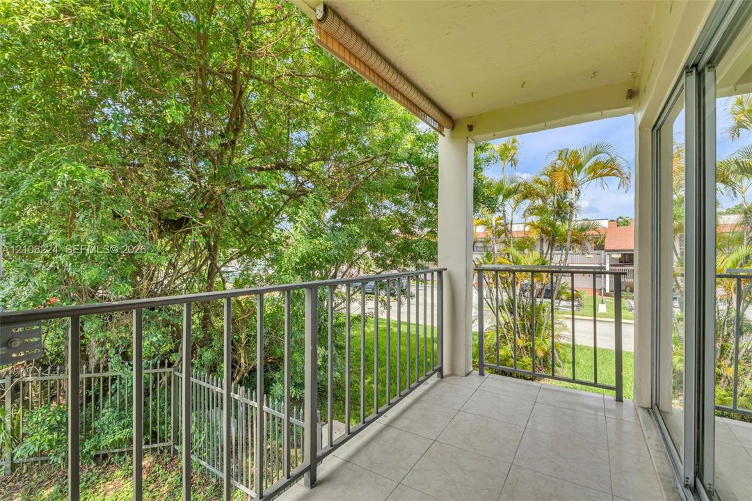 Covered balcony featuring tile flooring, metal railings, and a retractable fabric awning