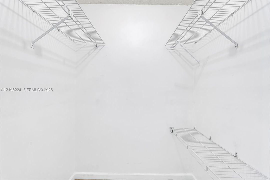 Walk-in closet featuring white walls and tiered white wire shelving