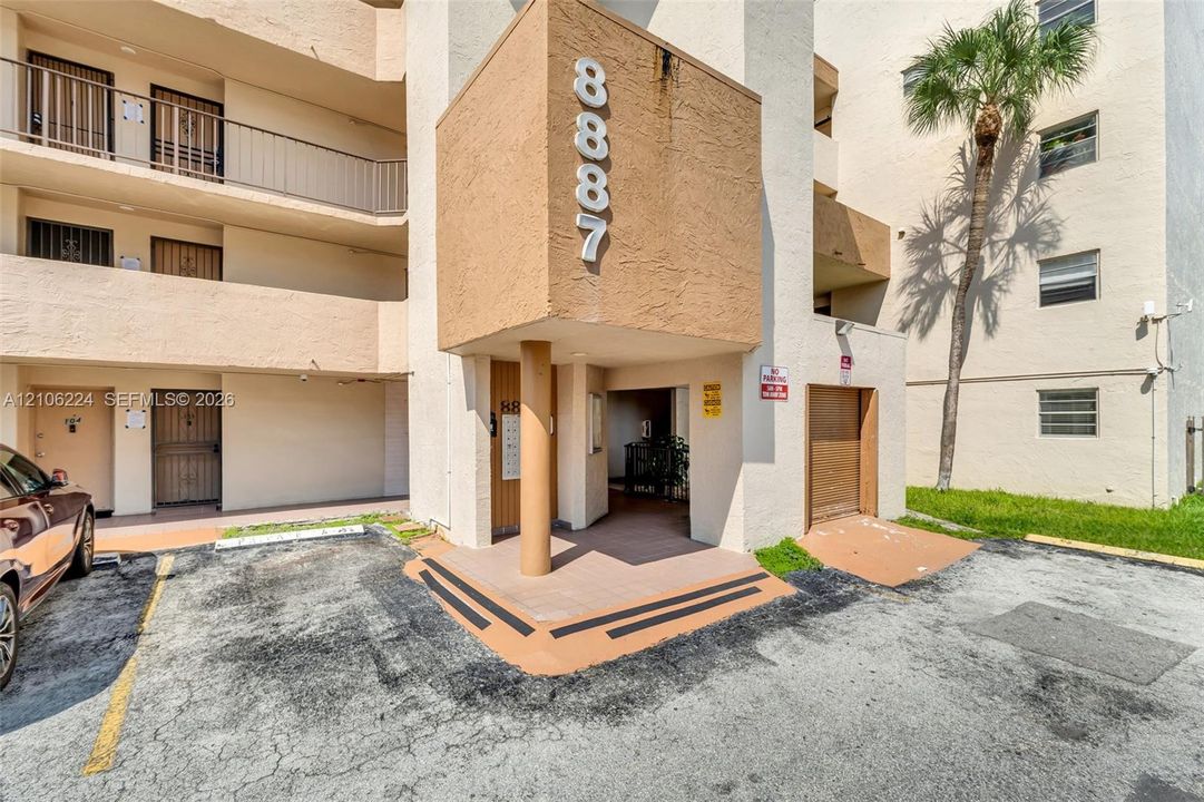 Multi-story stucco exterior featuring private balconies with metal railings, a covered entrance, and built-in wall-mounted numbering
