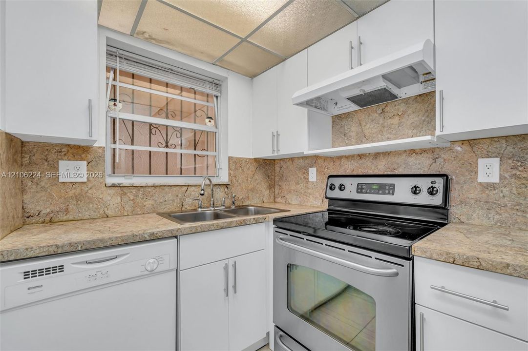 Kitchen featuring white cabinetry, stone-finish countertops, full-height stone-finish backsplash, stainless steel range, and integrated dishwasher