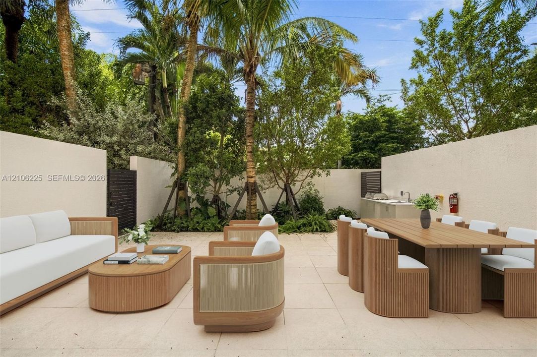 Private courtyard featuring limestone-style paving, high perimeter privacy walls, mature palm trees, and an integrated outdoor kitchen area with a built-in sink