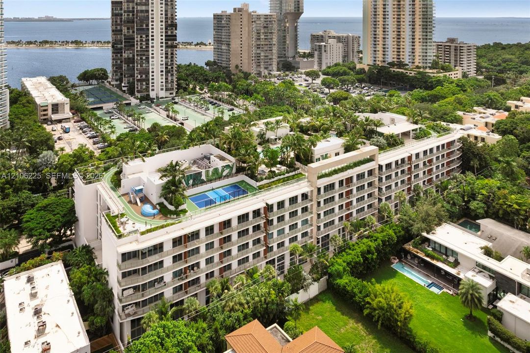 Multi-story residential complex featuring a rooftop sports court, integrated running track, and landscaped terrace greenery