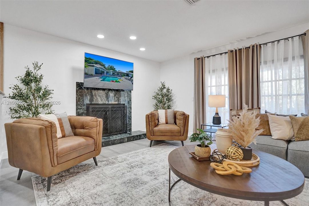 Fireplace featuring a full-height stone surround, recessed ceiling lighting, and large windows with multi-pane detailing