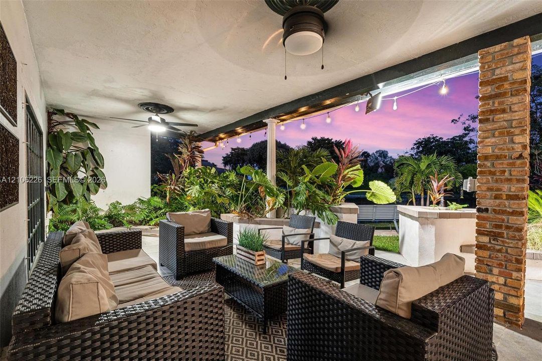 Covered patio featuring a brick support column, dual ceiling fans, and string lighting