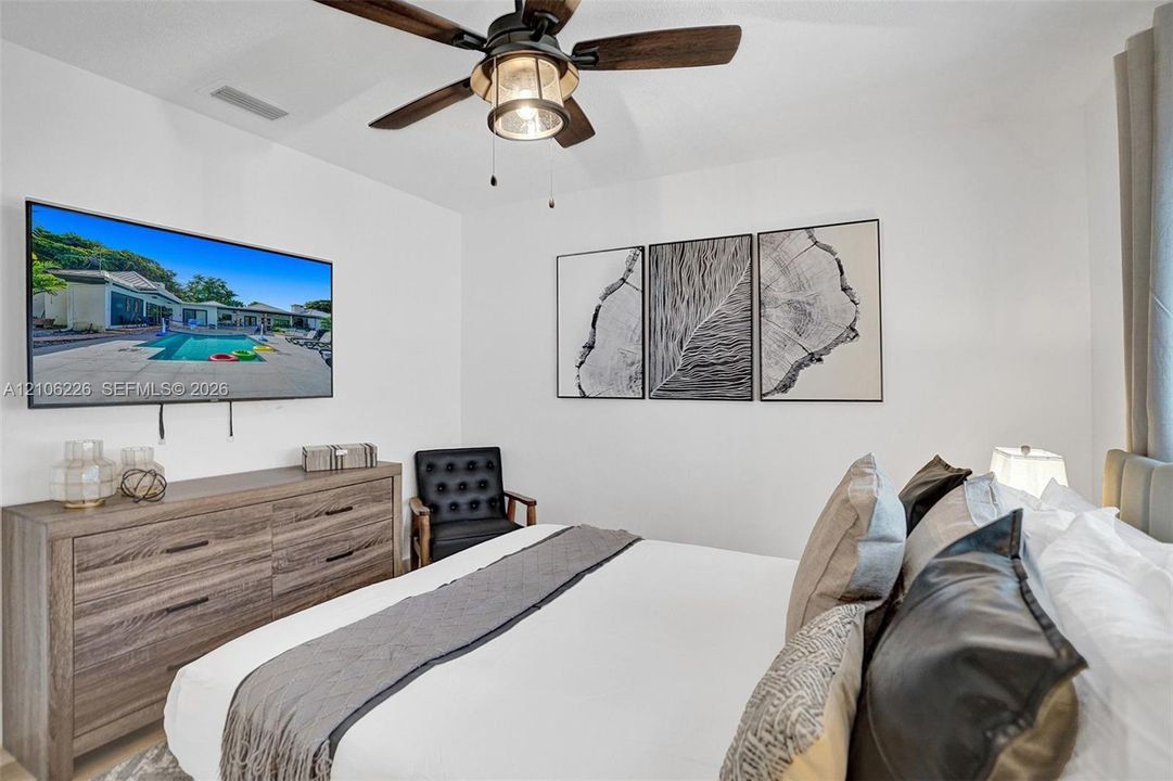 Bedroom featuring a high-contrast ceiling fan with integrated lighting