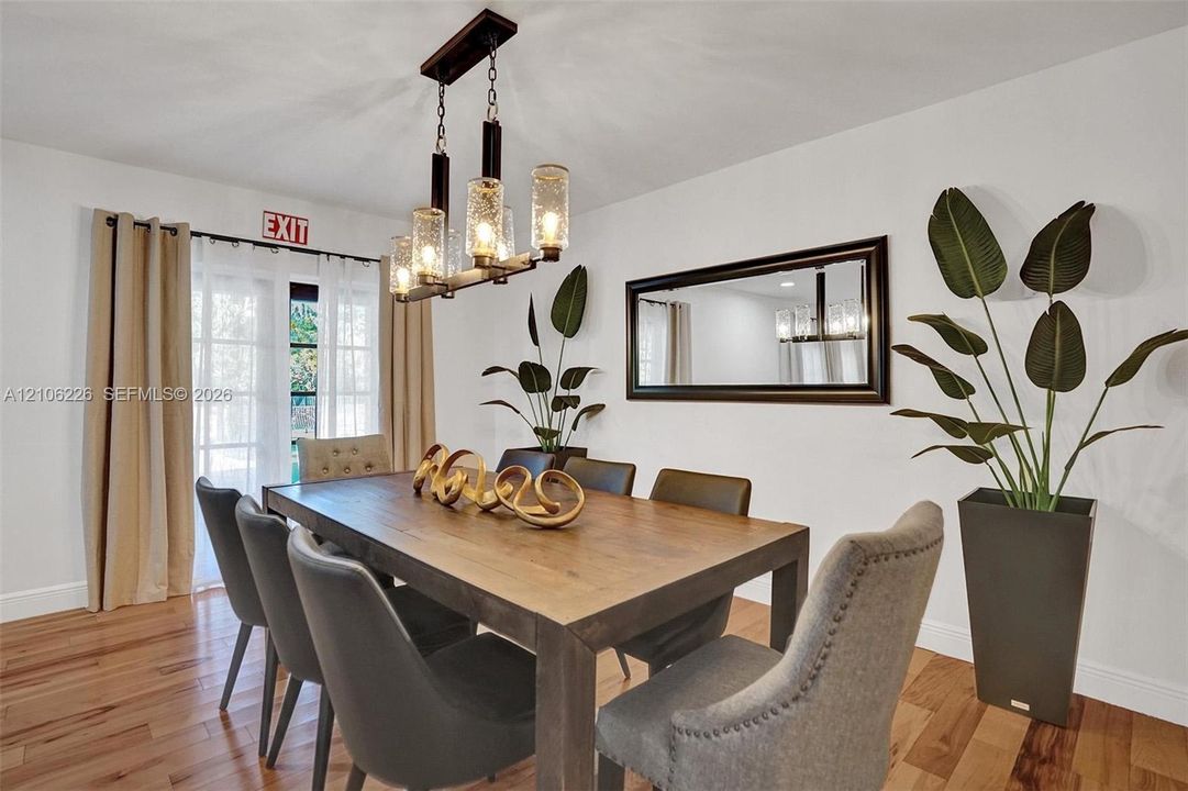 Hardwood flooring, multi-light linear chandelier with seeded glass shades, and double French doors