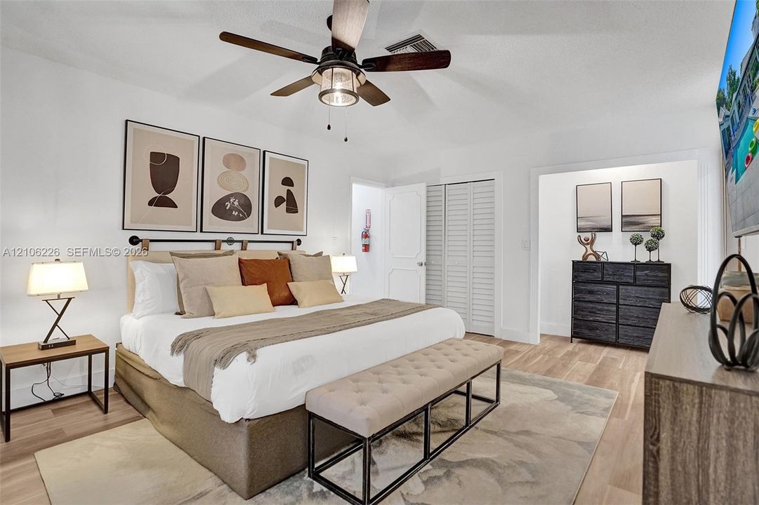 Wood-finish flooring, ceiling fan with integrated lighting, and louvered closet doors