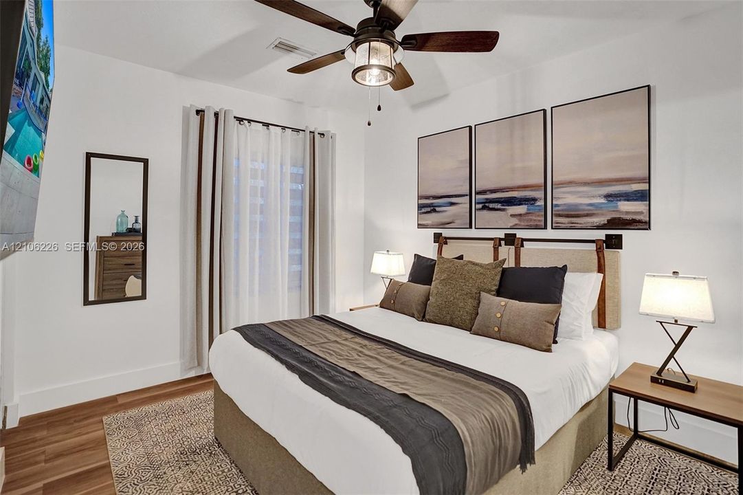 Wood-finish flooring, neutral walls, and a ceiling fan with integrated lighting