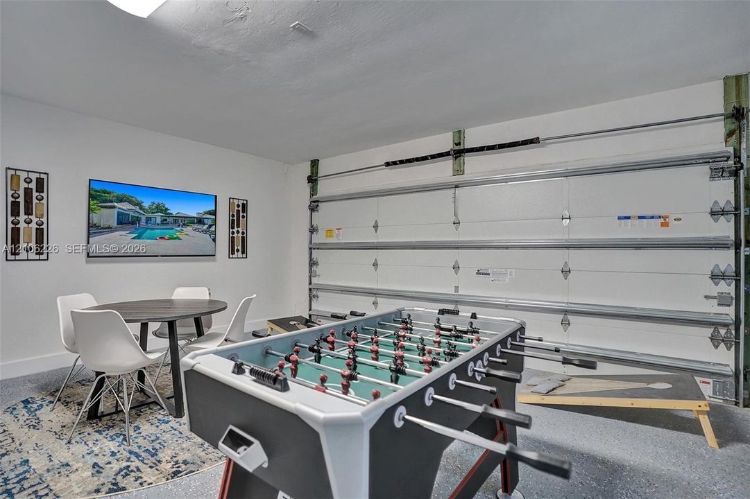 Finished interior space with epoxy-coated flooring, insulated roll-up garage door, and bright recessed lighting