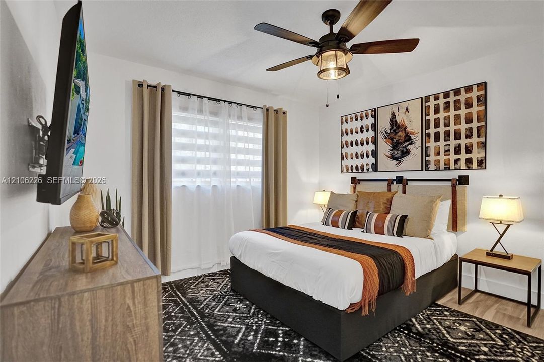 Bedroom featuring a ceiling fan with integrated lighting and wood-finish flooring