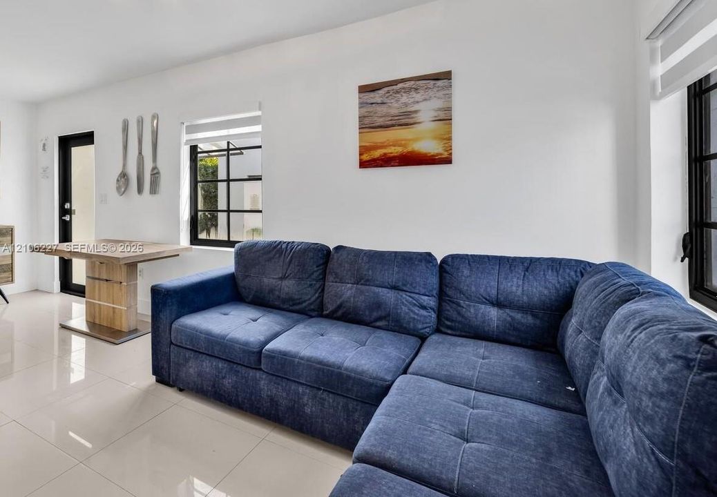 Large-format tile flooring, multi-pane black-trimmed windows, and a glass-paneled exterior door