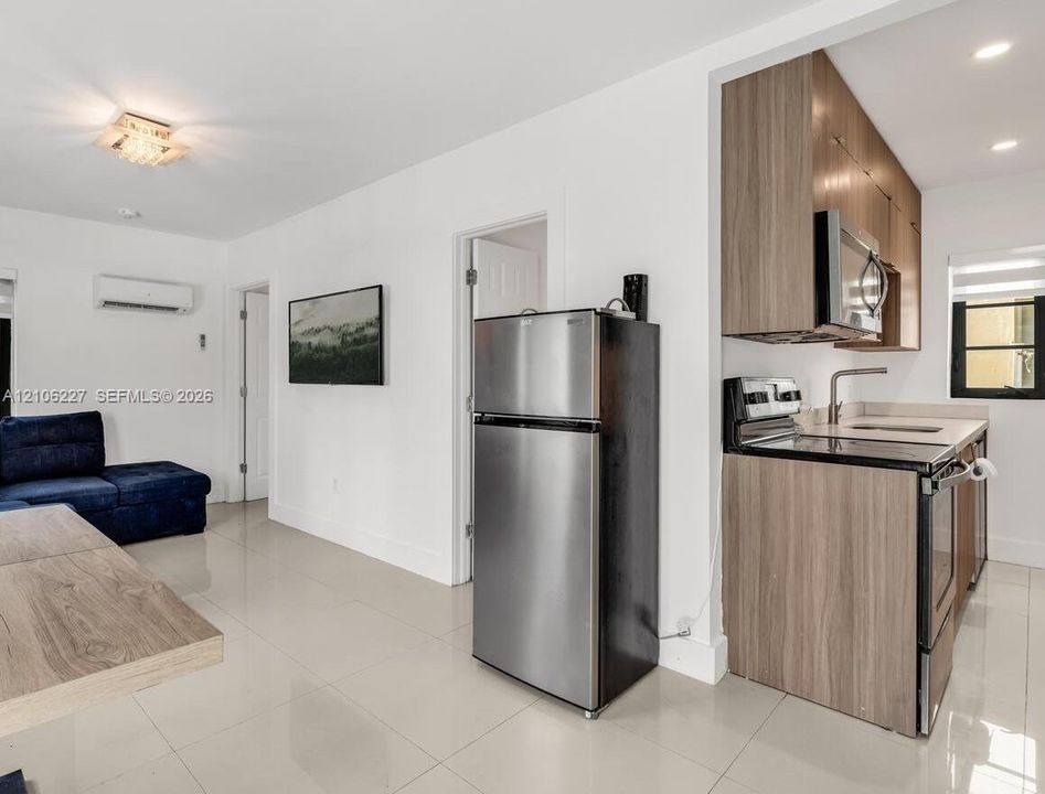 Kitchen featuring wood-finish cabinetry, stainless steel appliances, and solid-surface countertops, paired with tile flooring throughout the area