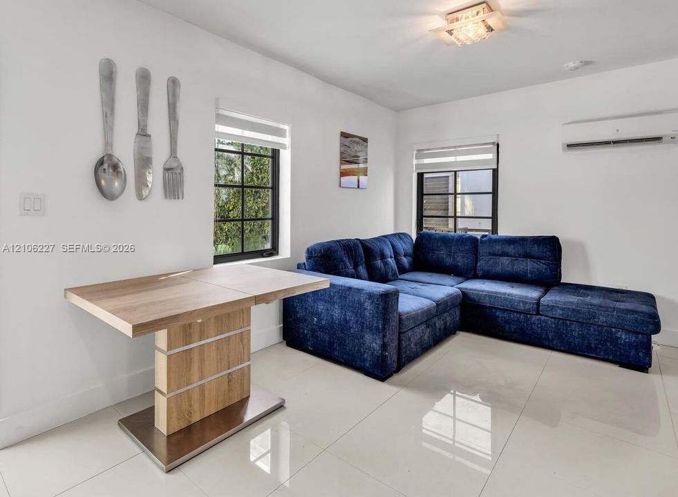 Polished tile flooring, multi-pane windows with grid detailing, wall-mounted climate control unit, and flush-mount glass ceiling light fixture