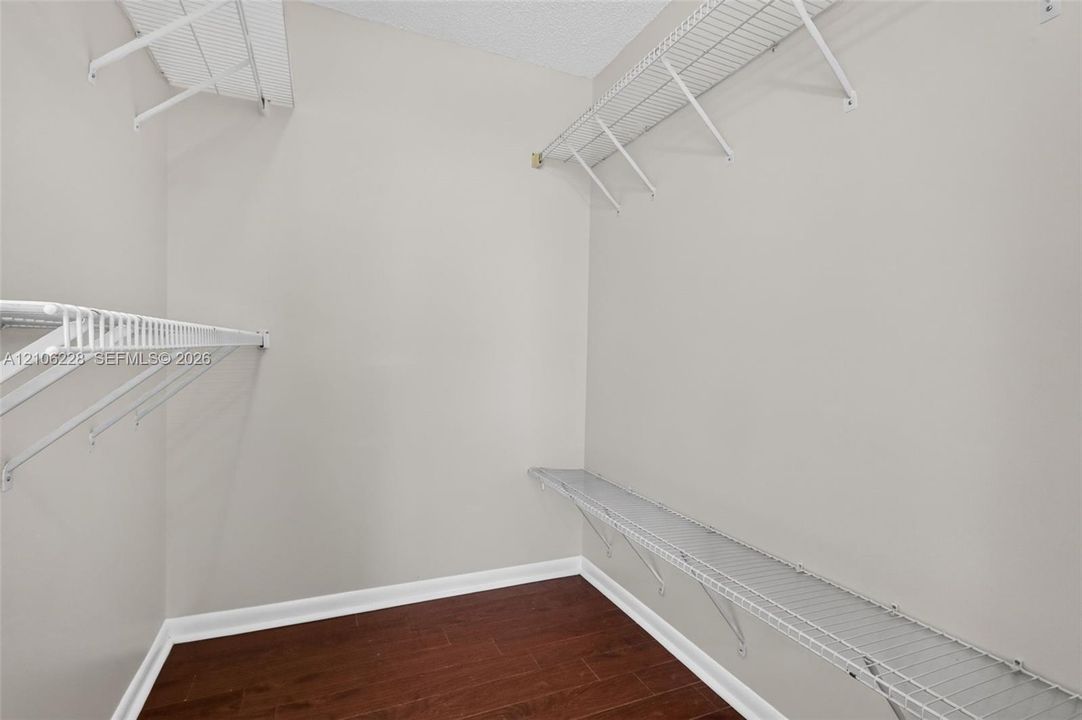 Walk-in closet featuring wood-finish flooring and multi-level white wire shelving