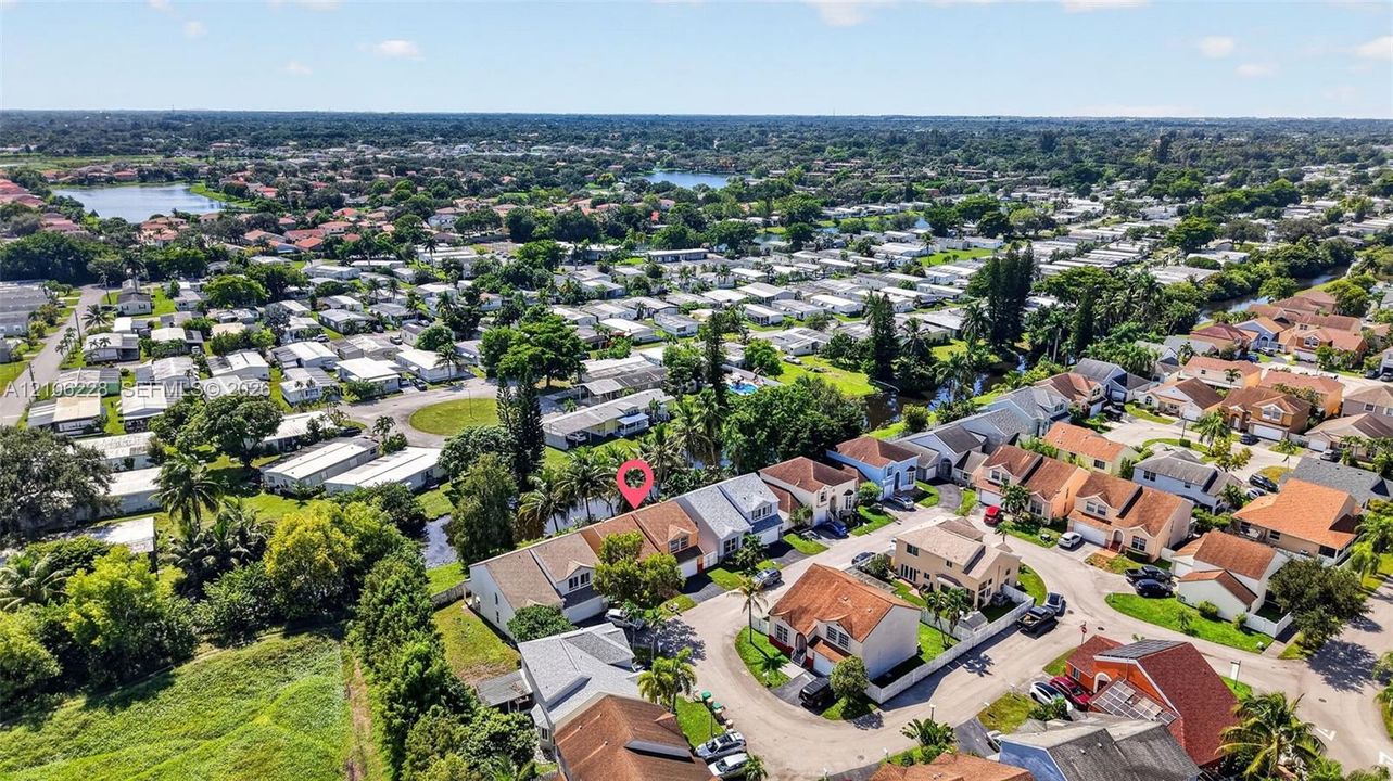 Aerial perspective of a multi-story residence featuring a shingled roof, attached garage, and rear waterfront positioning within a established residential community