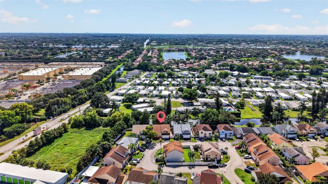 Aerial perspective of a multi-unit residential community featuring cul-de-sac street layouts, shingle-roof structures, mature tree canopy, and proximity to regional waterways