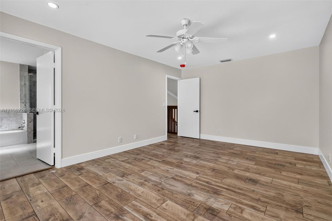 Room featuring wood-finish tile flooring, recessed lighting, a white ceiling fan with integrated light kit, and solid-core interior doors