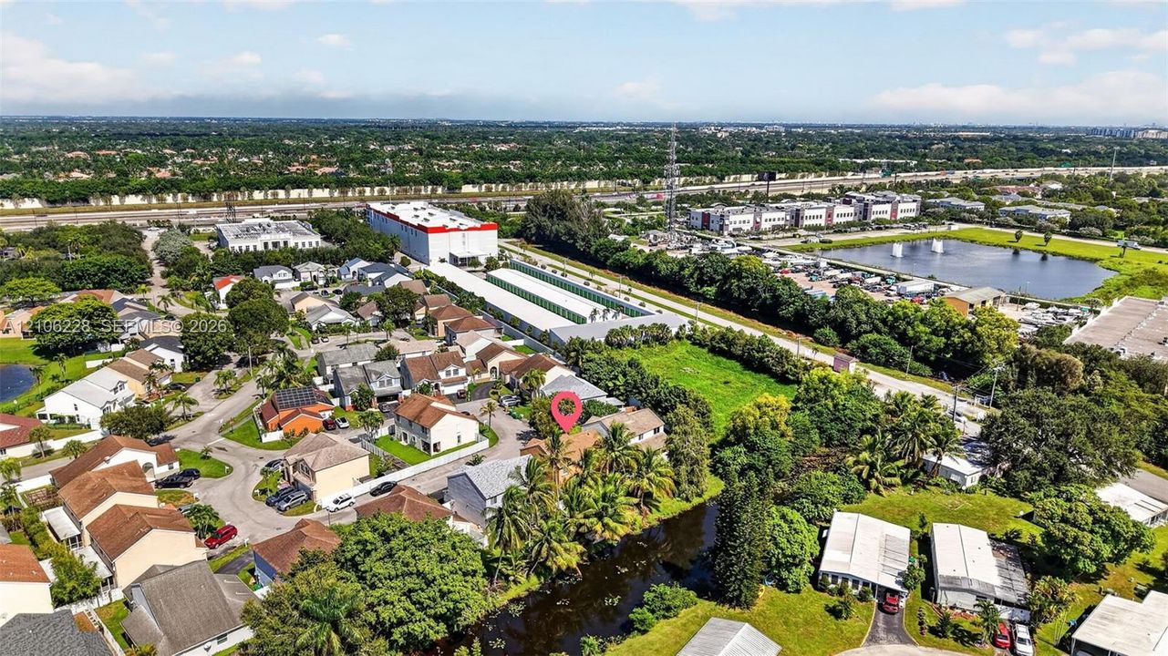Aerial perspective featuring a residential lot with mature palm trees and a water-front boundary