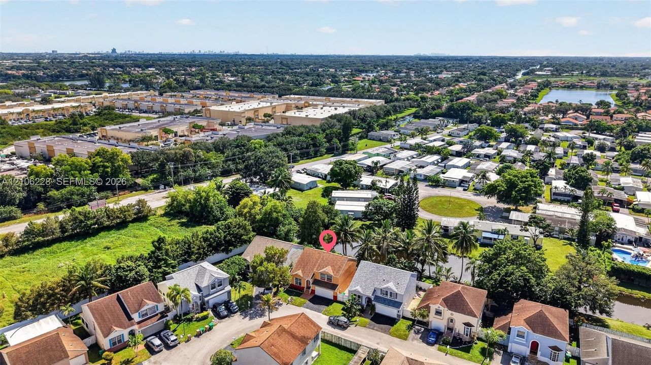 Aerial perspective of a multi-story residence featuring a shingled roof, attached garage, and mature palm trees