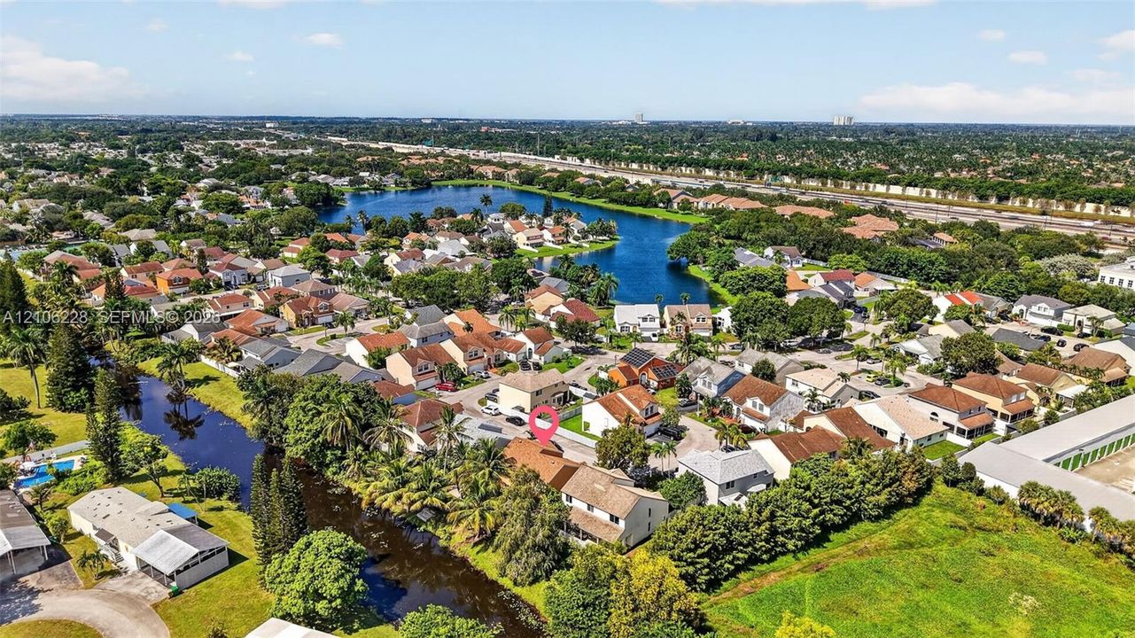 Aerial perspective of a multi-level suburban residence featuring a concrete tile roof, paved driveway, and placement along a waterfront canal