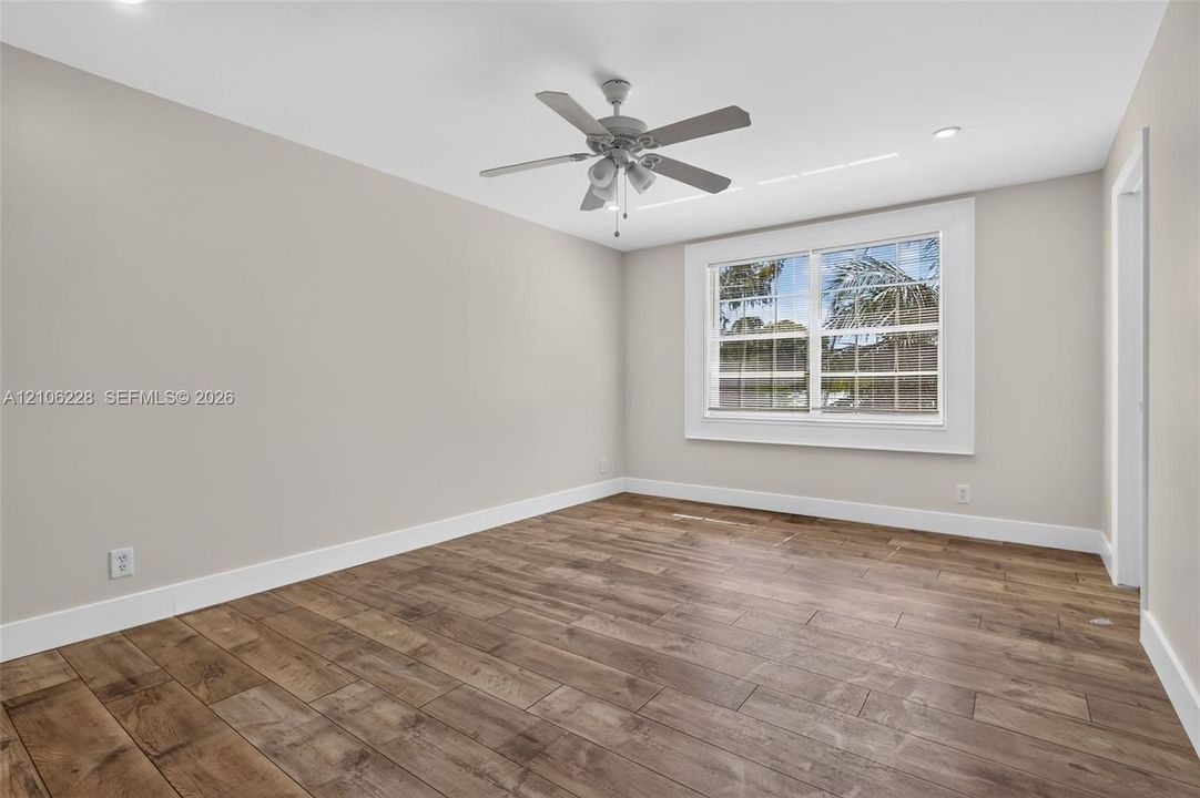 Neutral-toned interior featuring wood-finish flooring, recessed lighting, and a ceiling fan with integrated lighting fixtures