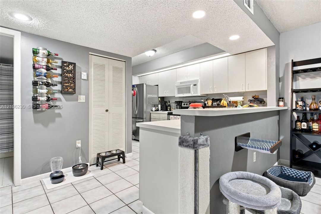 Kitchen featuring white cabinetry, stainless steel appliances, tile flooring, recessed lighting, and a breakfast bar