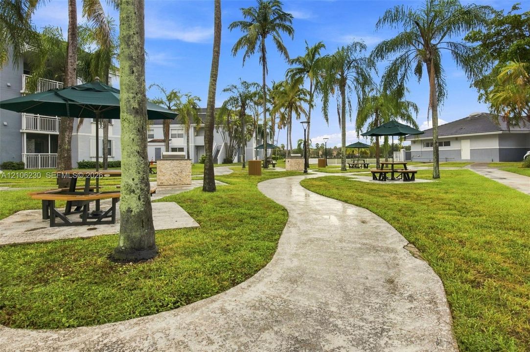 Landscaped grounds featuring mature palm trees, concrete walkways, and designated outdoor picnic areas