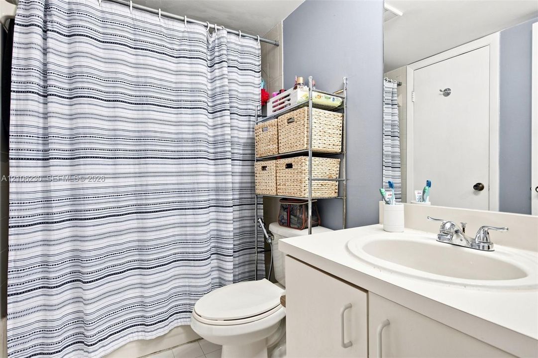 Bathroom featuring a vanity with an integrated basin, dual-handle chrome faucet, solid-surface countertop, and a full-width wall mirror