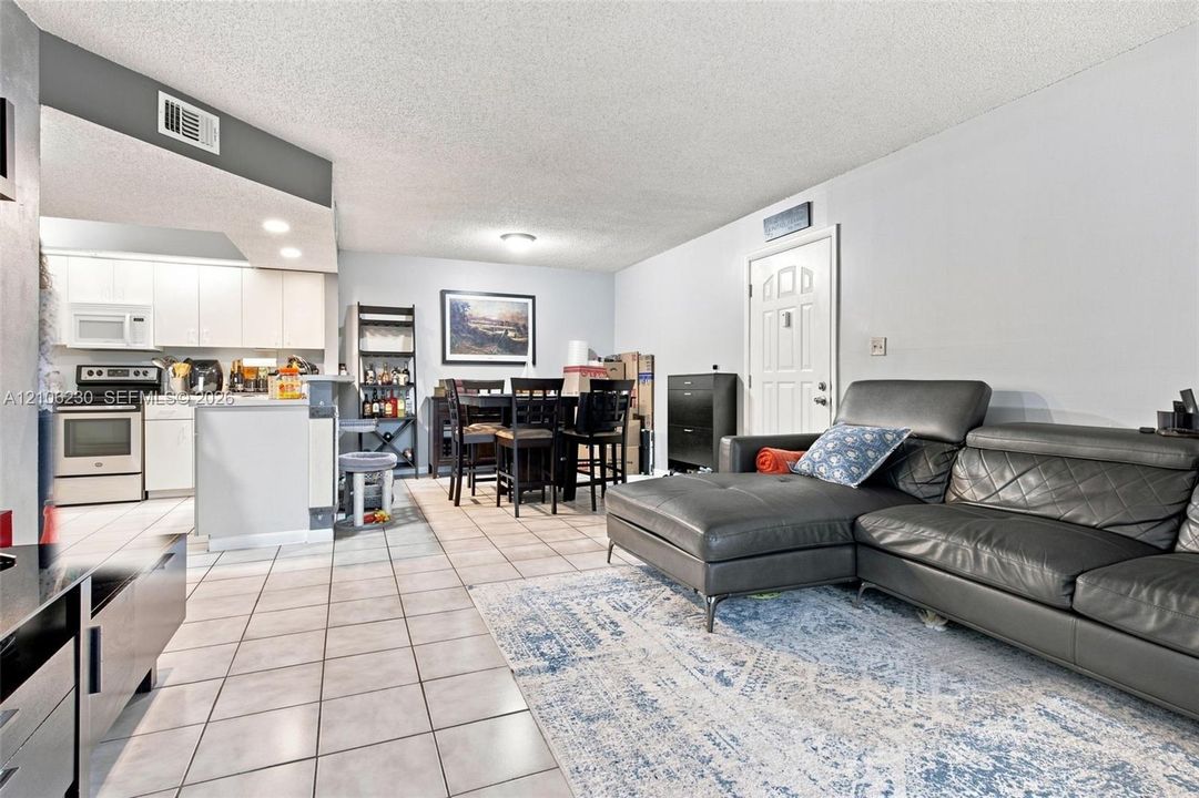 Open-concept layout featuring light-toned tile flooring, white cabinetry, a breakfast bar, and recessed lighting