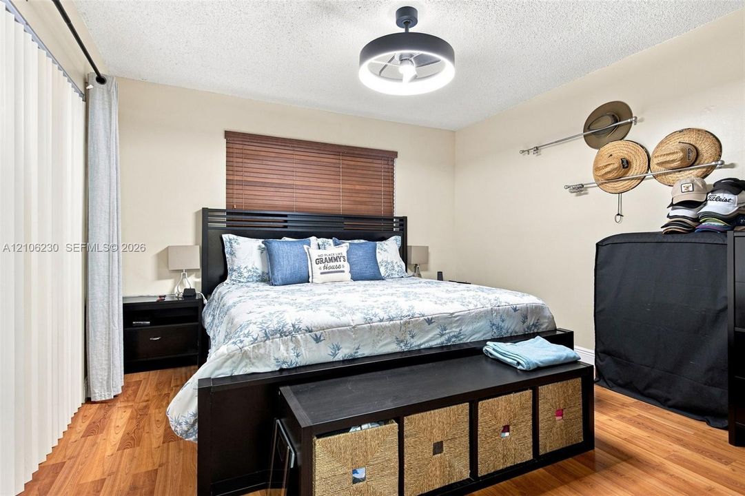Wood-finish flooring, horizontal window blinds, and a contemporary circular flush-mount ceiling light fixture