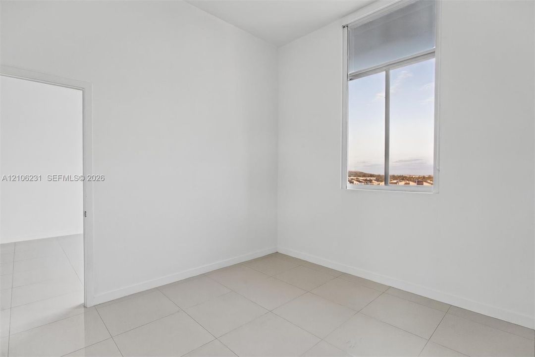 Bedroom with high ceilings, oversized window with exterior scenery, neutral walls, and 24x24 tile flooring