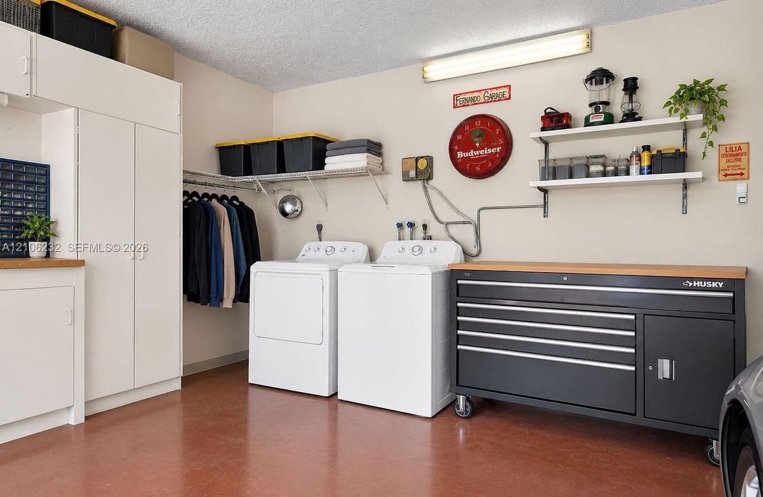 Garage featuring epoxy flooring, built-in cabinetry, dual wall-mounted shelving units, and linear fluorescent lighting