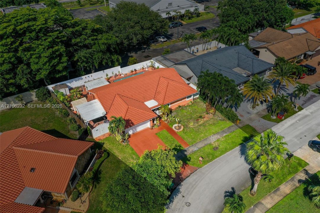 Single-story residence featuring a terracotta-tiled roof, an integrated two-car garage, an enclosed rear pool area, and a private concrete driveway
