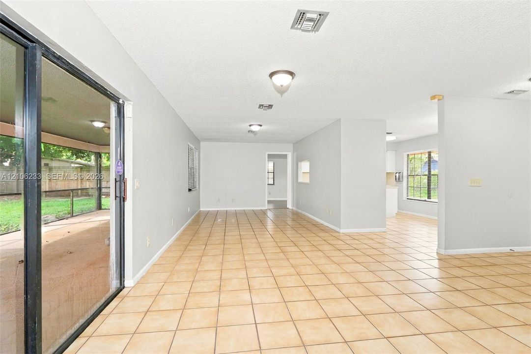 Open-concept interior featuring neutral wall tones, large-format ceramic tile flooring, recessed and flush-mount lighting, and expansive sliding glass doors