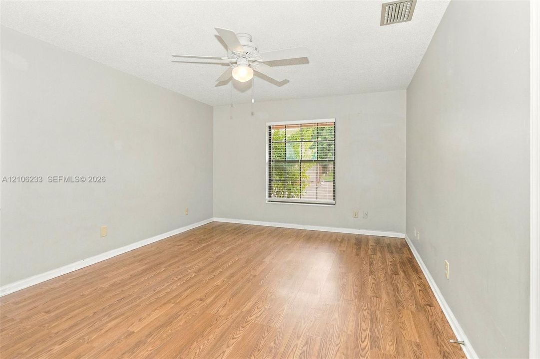 Interior space featuring wood-finish flooring, a multi-pane window, and a central ceiling fan with an integrated light fixture