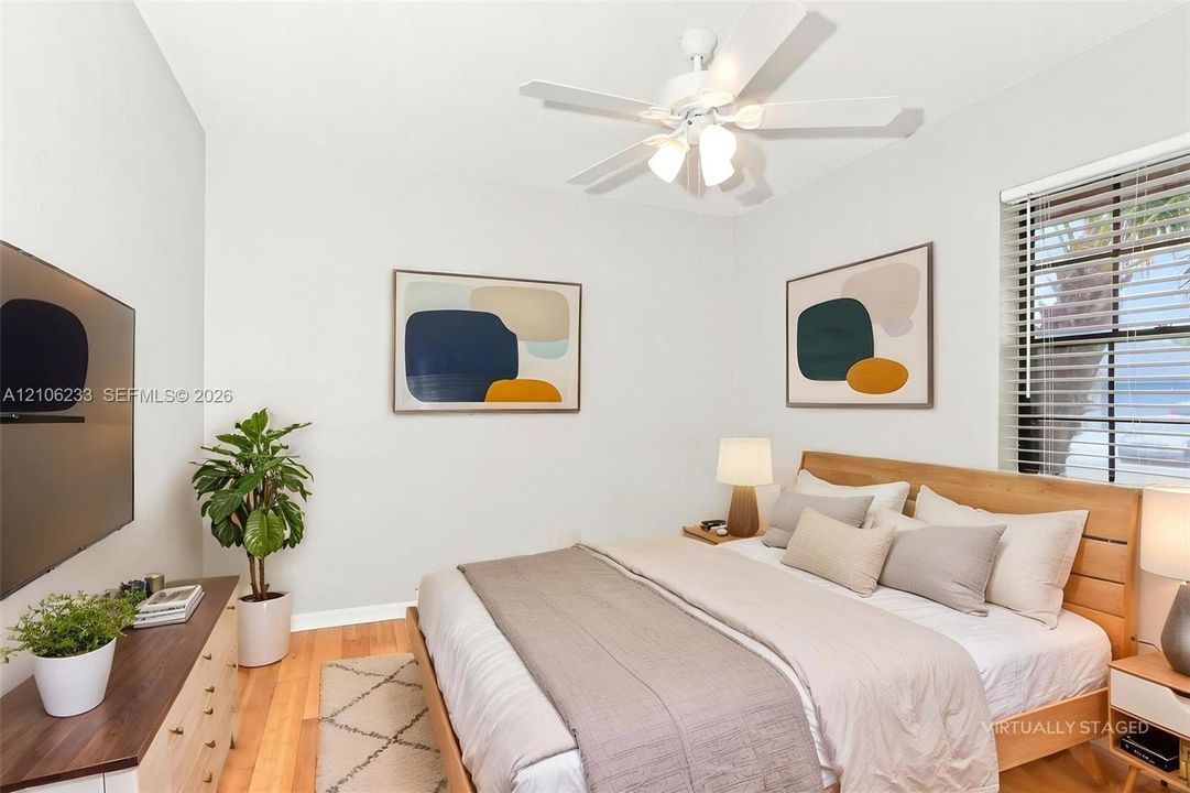 Room featuring wood-finish flooring, a white ceiling fan with integrated light fixture, and blinds installed on the window