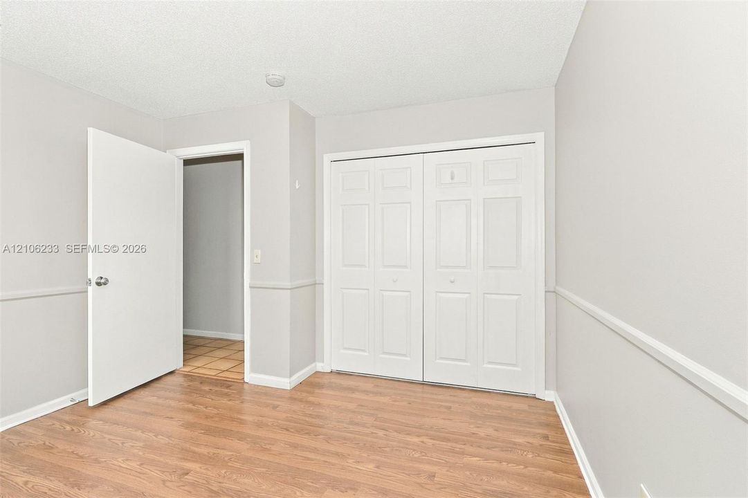 Room featuring wood-finish flooring, chair rail molding, and a double-door closet with paneled detailing