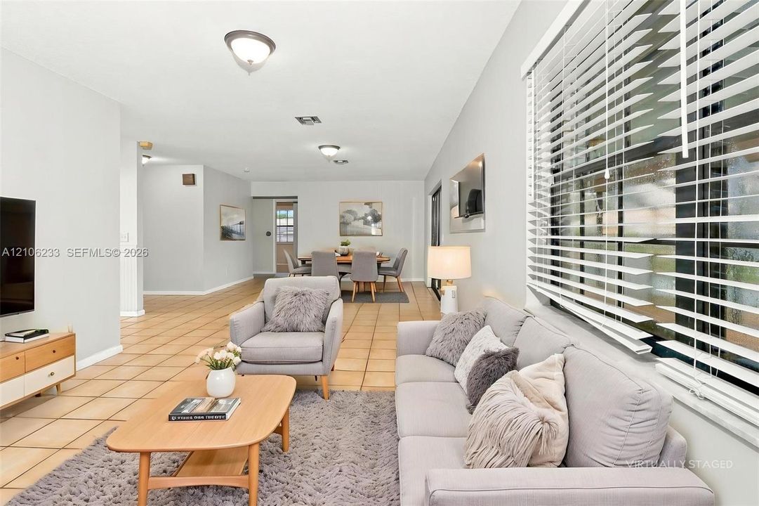 Open-concept interior featuring light-toned tile flooring, large multi-pane windows, and recessed ceiling lighting